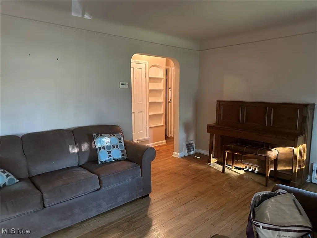 Living room with arched walkways and wood-type flooring