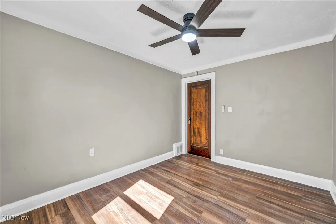 Spare room featuring ornamental molding, dark wood-style flooring, and a ceiling fan