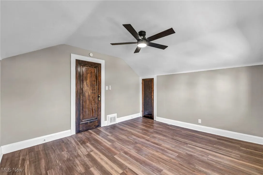 Additional living space with vaulted ceiling, dark wood-style floors, and ceiling fan