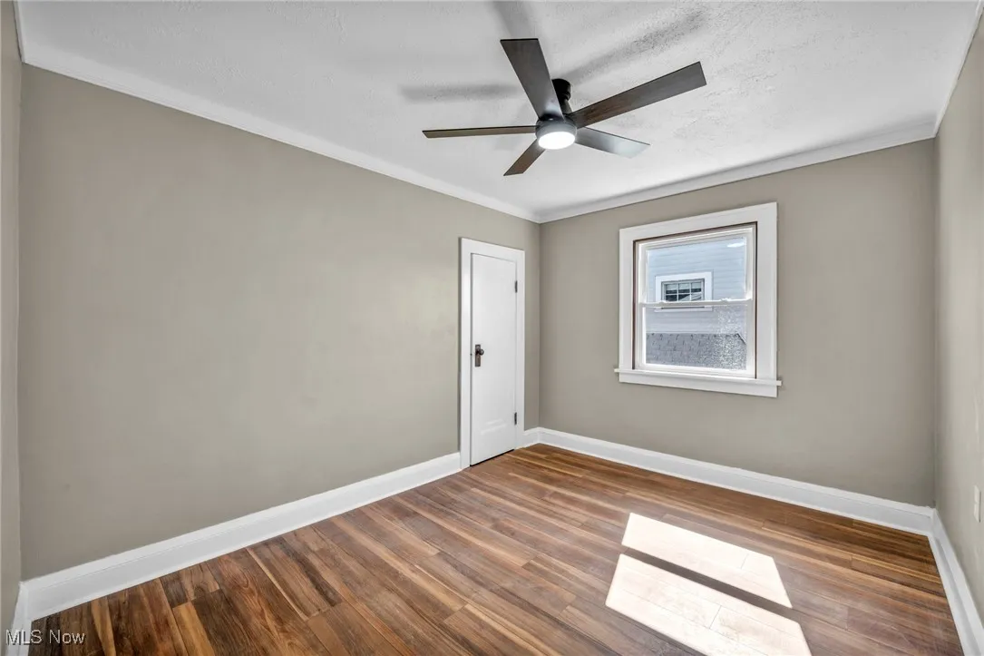 Empty room featuring ornamental molding, wood finished floors, a textured ceiling, and ceiling fan