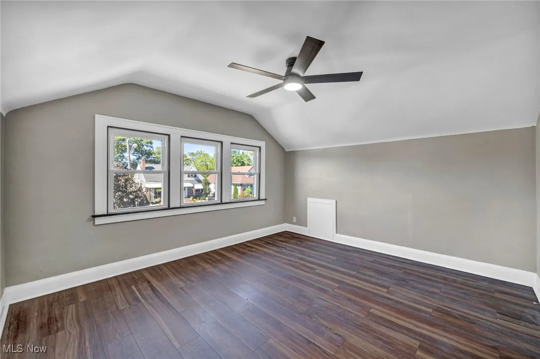 Bonus room with lofted ceiling, dark wood-style flooring, and ceiling fan