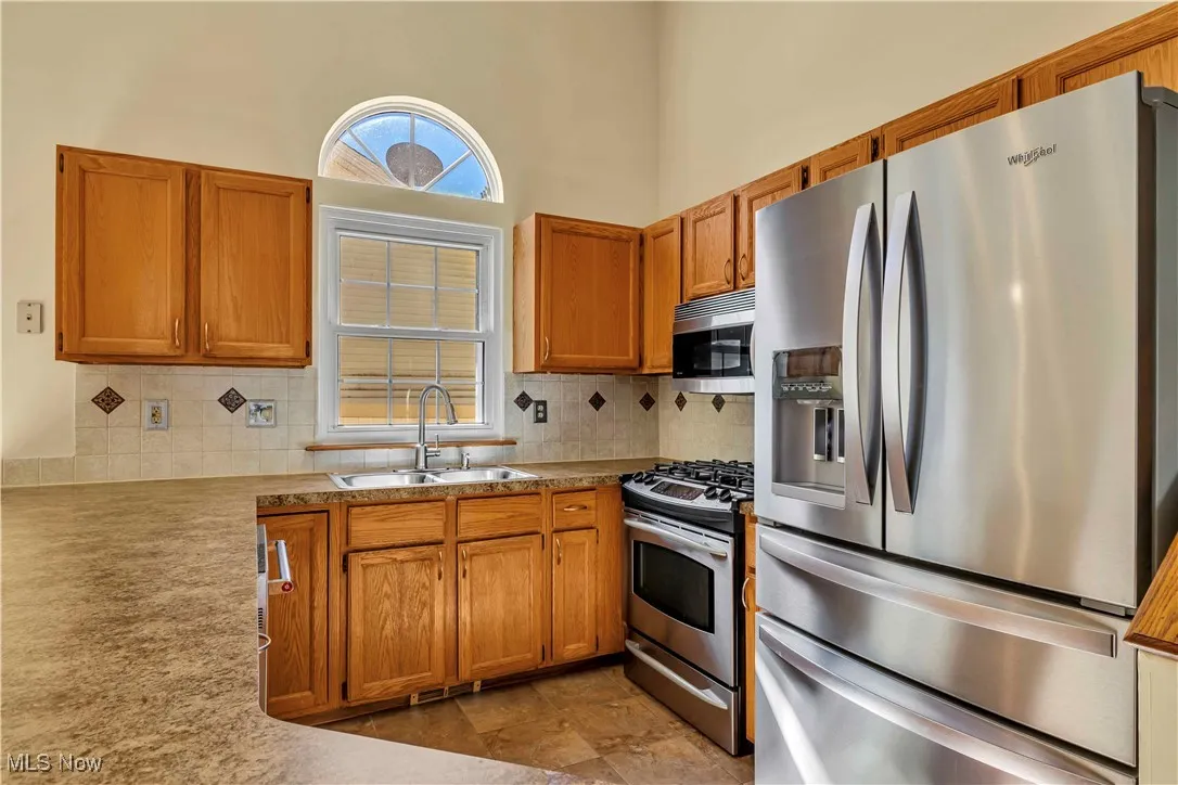 Open concept kitchen with beautiful window over the sink. Oak cabinets, modern hardware, stainless steel appliances and tiled floor.