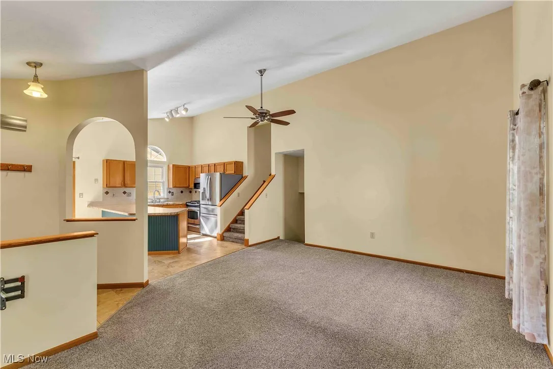 Open concept main floor with vaulted ceilings. View of the formal living room featuring neutral carpet, neutral walls and ceiling fan.