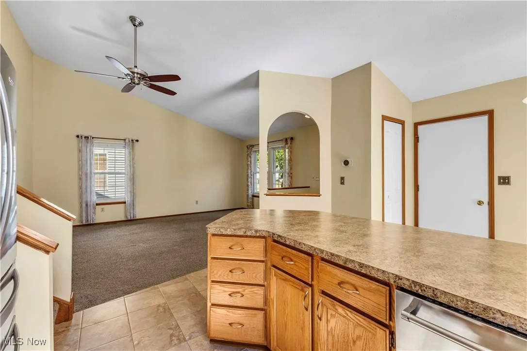Kitchen overlooks eat-in dining area and living room. Kitchen features oak cabinetry, modern hardware, stainless steel appliances, laminate countertops and tiled backsplash.