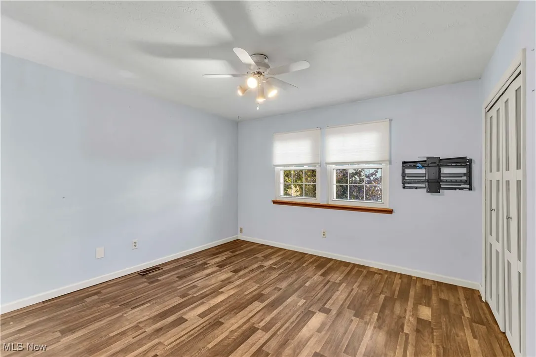 Spacious primary bedroom featuring updated flooring, modern paint color on the walls, two closets and a ceiling fan.