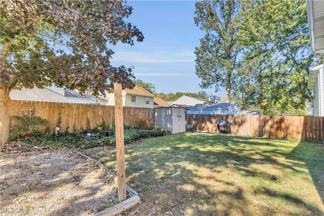 Backyard featuring gravel firepit area, fish pond and storage shed.