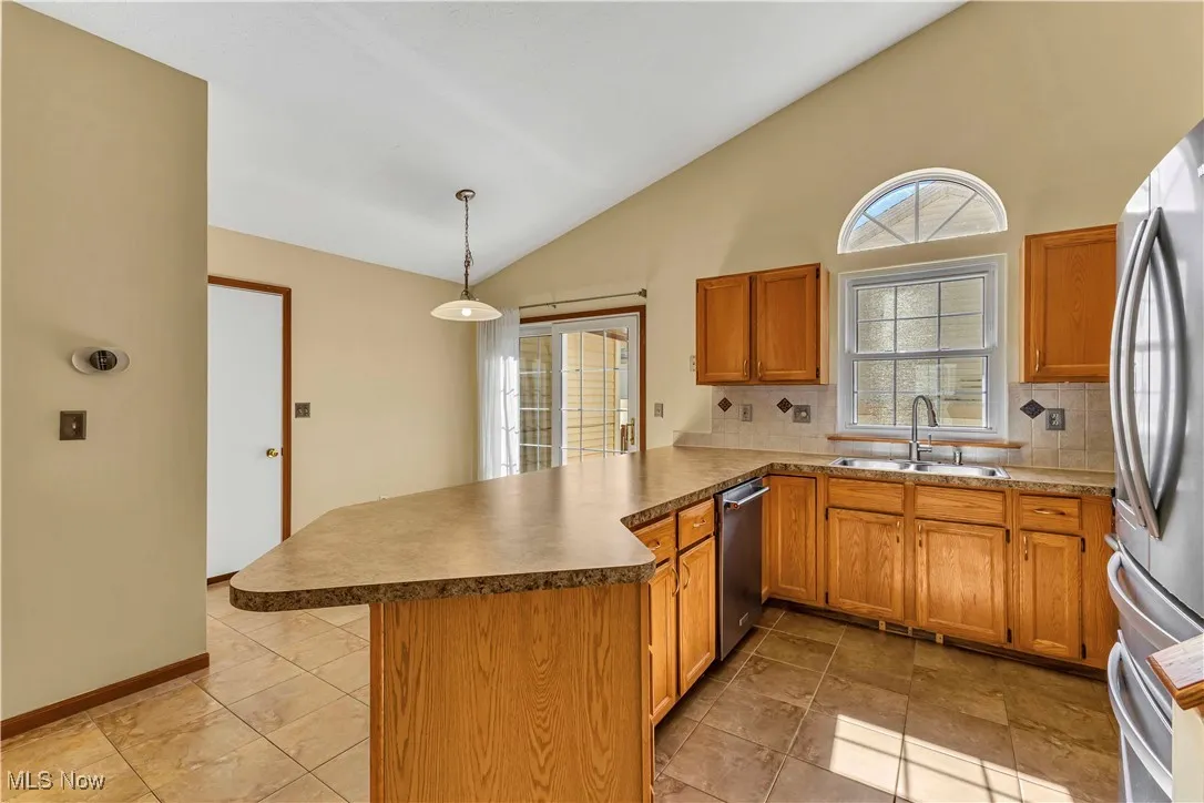 Open concept kitchen with beautiful window over the sink. Oak cabinets, modern hardware, stainless steel appliances and tiled floor. Large breakfast bar/peninsula that offers a place for additional seating for casual dining.