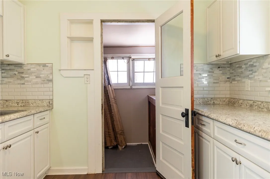 Kitchen featuring modern backsplash and countertops, white cabinets, bamboo floor, and walk-in pantry