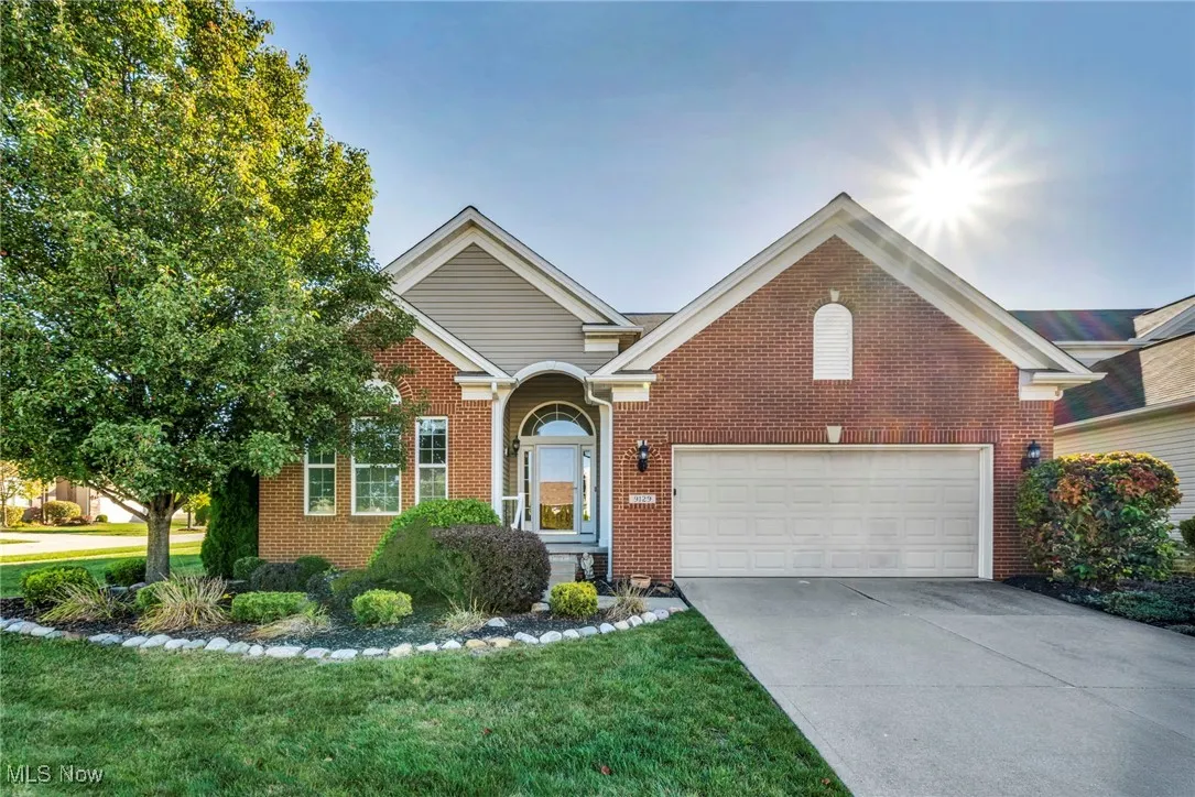 View of front of home with driveway, brick siding, a front lawn, and an attached garage