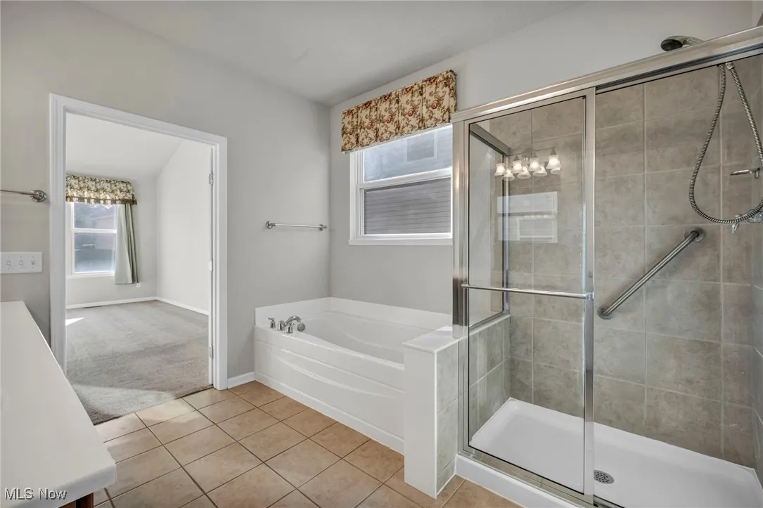 Bathroom with light tile patterned floors, a shower stall, a garden tub, and vanity