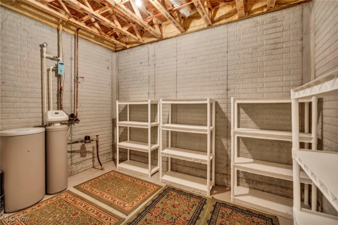 Unfinished basement featuring a water softener and brick wall