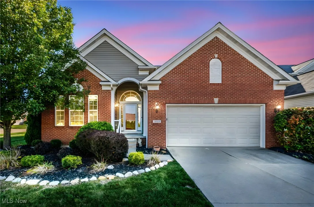 View of front of home featuring brick siding, driveway, and a garage