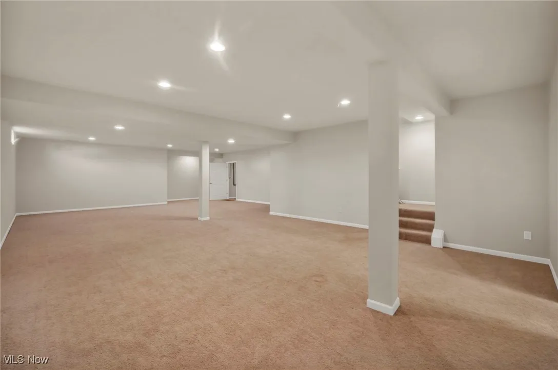 Finished below grade area featuring recessed lighting, light carpet, and stairs