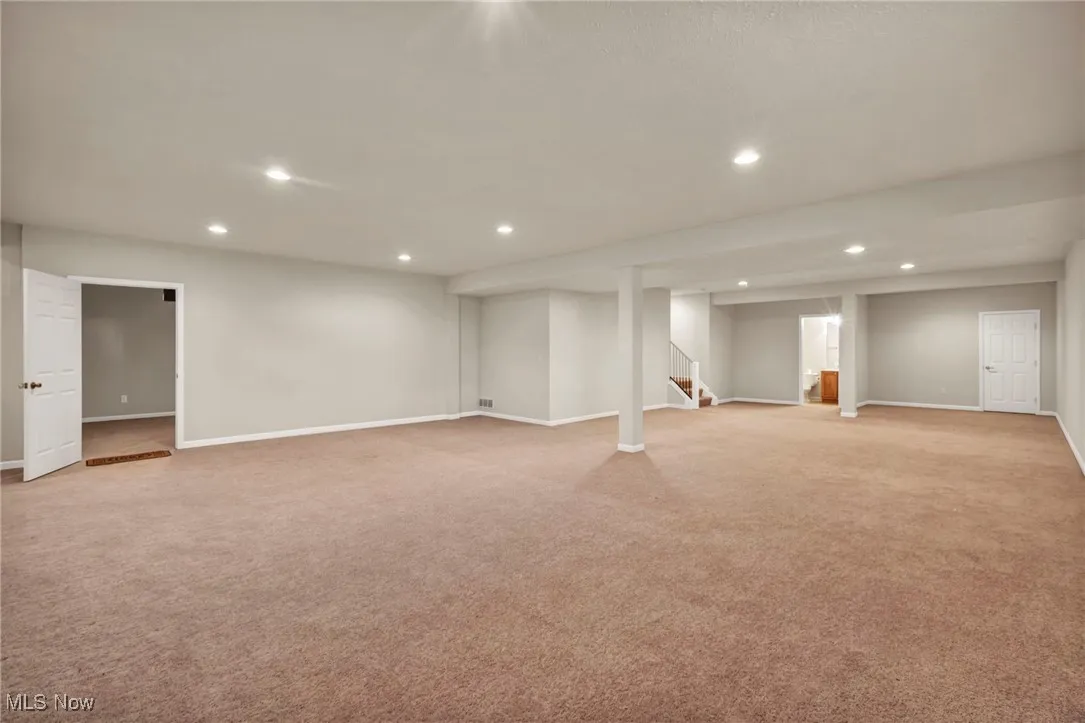 Finished basement featuring recessed lighting, light carpet, and stairway
