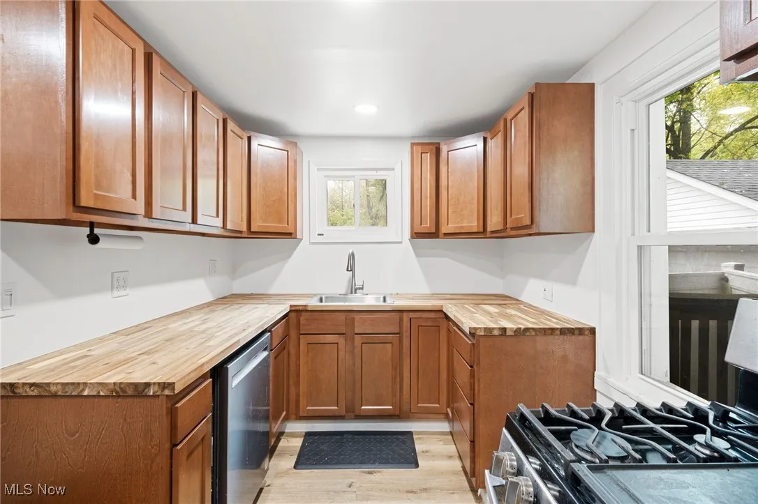 Kitchen featuring wooden counters, brown cabinets, light wood-type flooring, appliances with stainless steel finishes, and recessed lighting