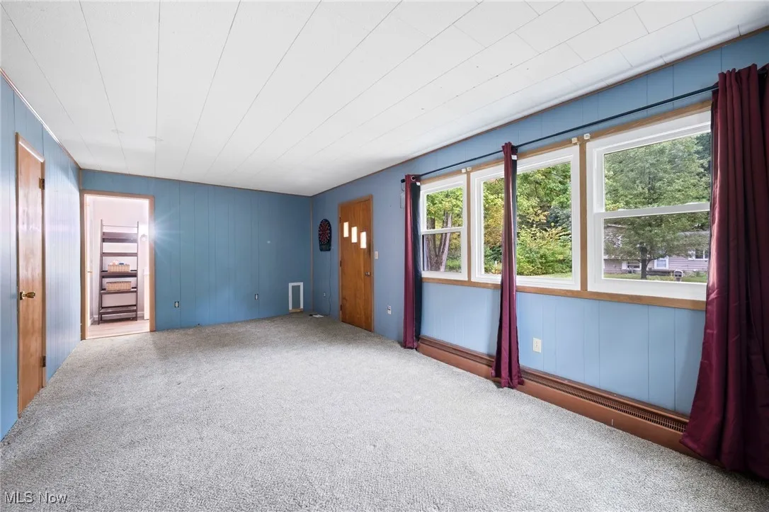 Carpeted empty room featuring wooden walls