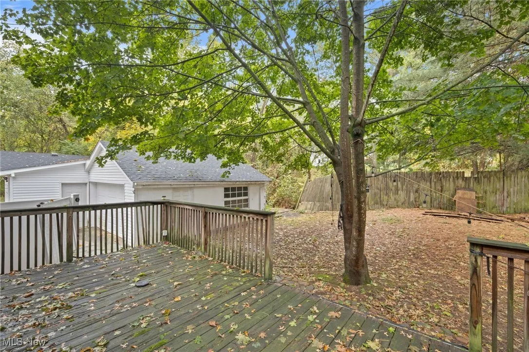 Wooden terrace featuring an outdoor structure and a garage