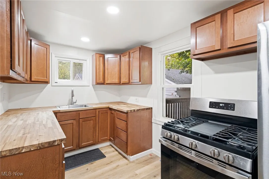 Kitchen with stainless steel range with gas stovetop, brown cabinetry, butcher block counters, light wood-type flooring, and recessed lighting