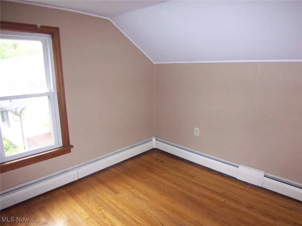 Bedroom #3 with dark wood-style floors, and lofted ceiling