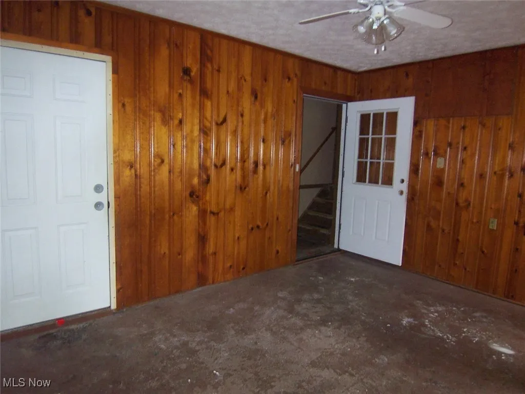 Mud room with paneled wood walls, and ceiling fan