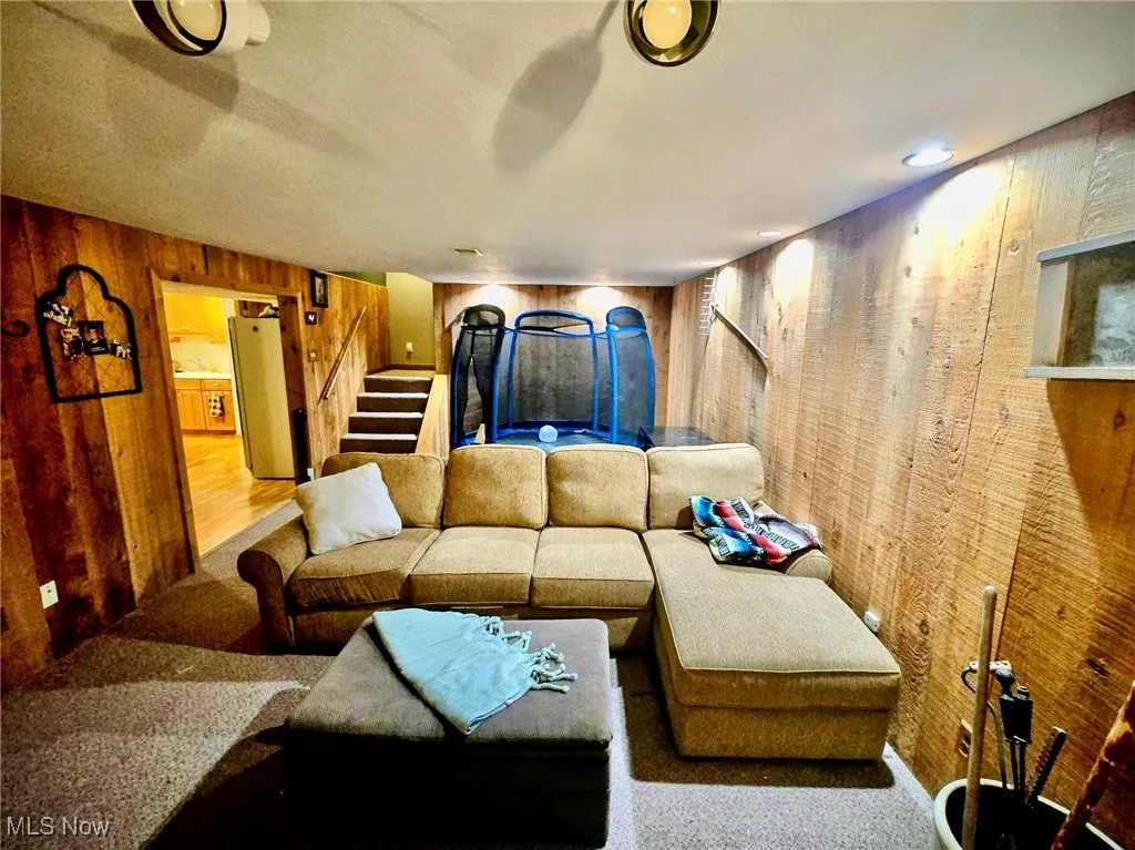 Living room with wood walls, stairs, and carpet
