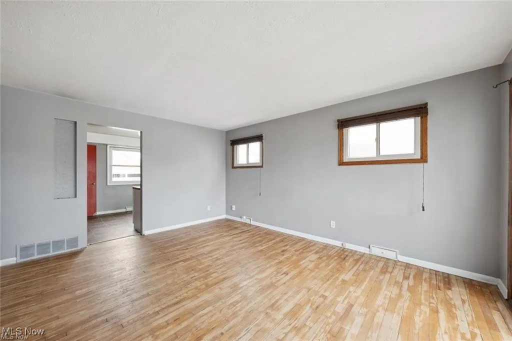 Unfurnished room with healthy amount of natural light, light wood finished floors, and a textured ceiling