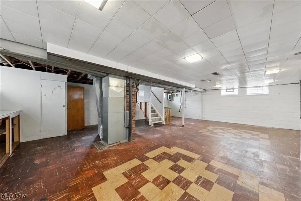 Below grade area with stairs, dark flooring, and heating unit