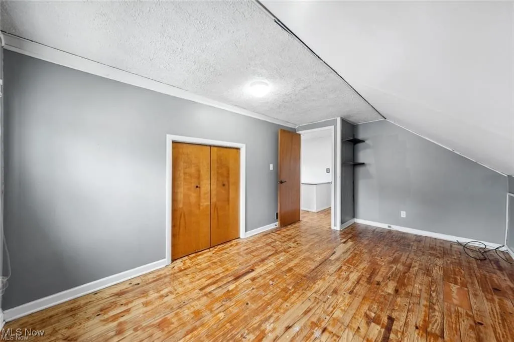 Bonus room featuring a textured ceiling, hardwood / wood-style floors, and lofted ceiling