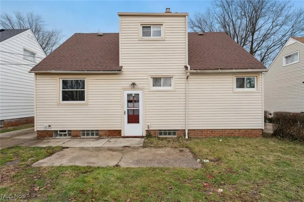 Rear view of house featuring roof with shingles, a yard, and a patio