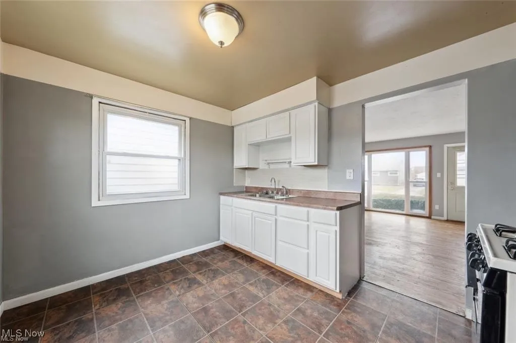 Kitchen featuring black gas range oven, white cabinets, and plenty of natural light