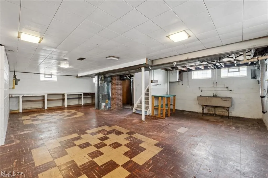 Below grade area featuring tile patterned floors, stairs, and heating unit
