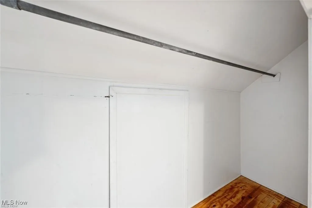 Walk in closet featuring wood finished floors and vaulted ceiling