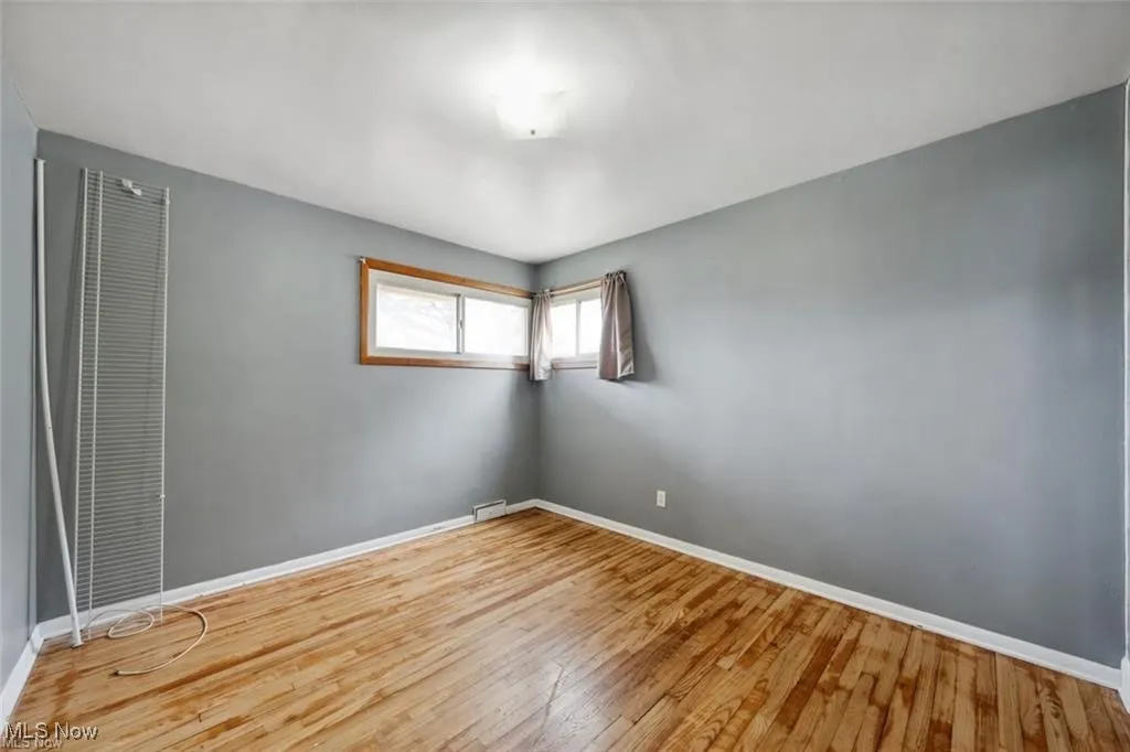 Empty room with hardwood / wood-style flooring and a heating unit