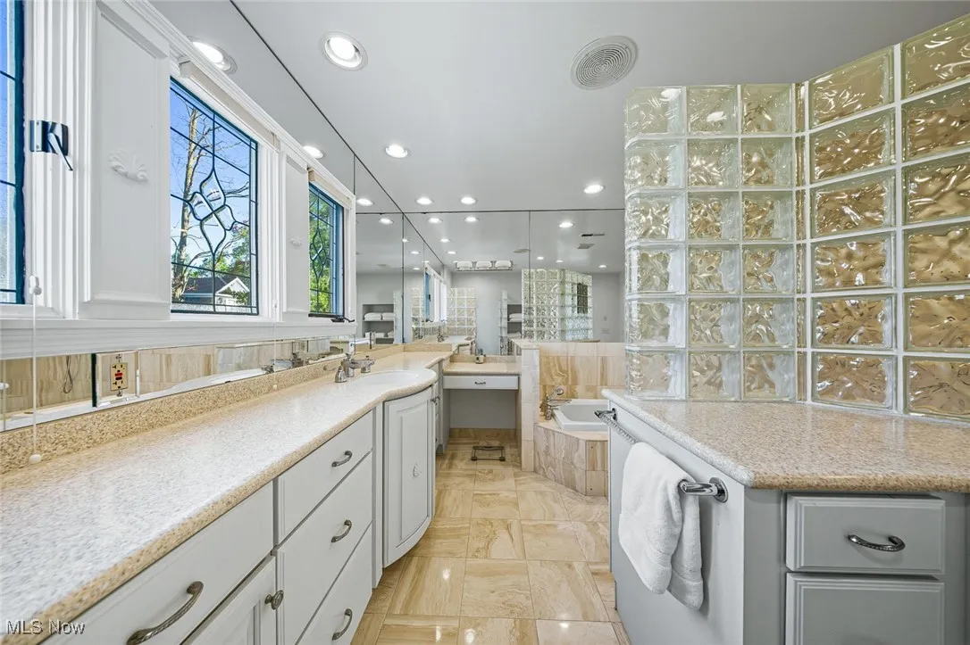 Bathroom with recessed lighting, vanity, and a bath