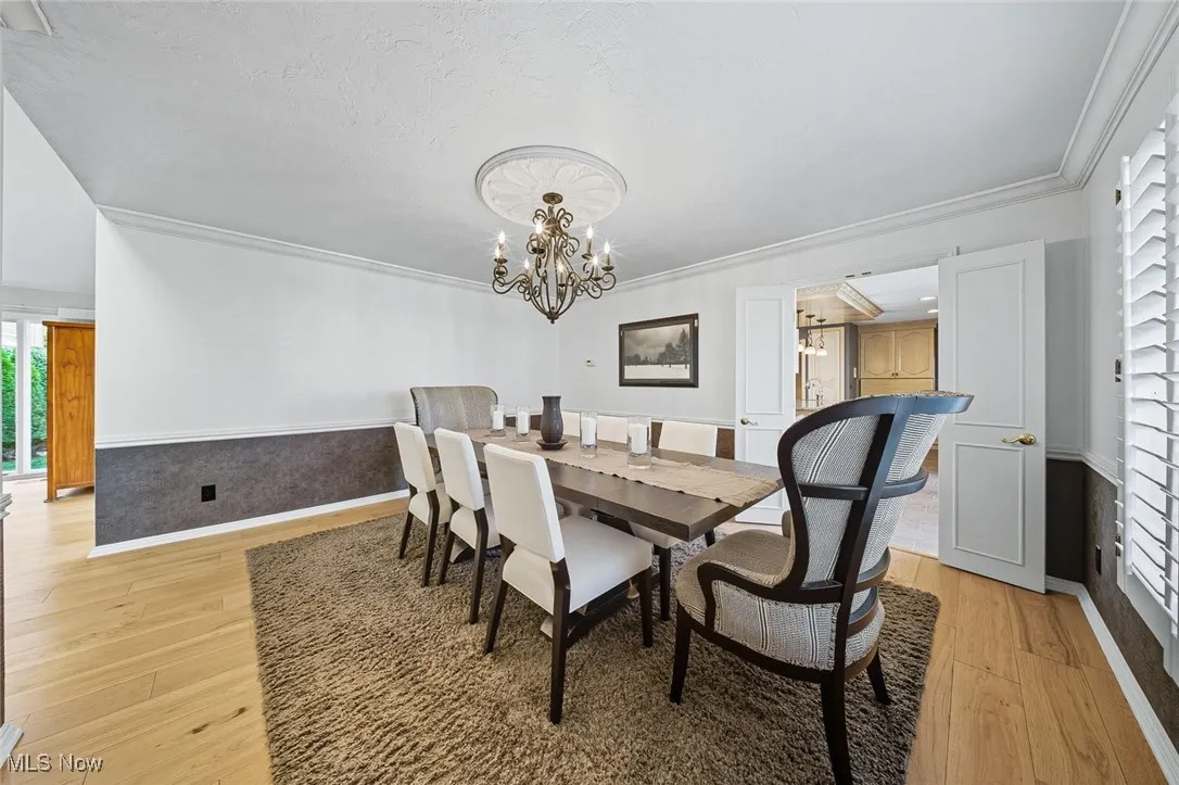 Dining room with light wood-style flooring, a chandelier, and ornamental molding