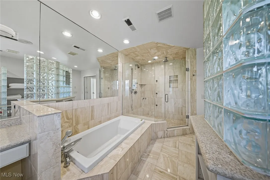 Full bathroom with a shower stall, a bath, and recessed lighting