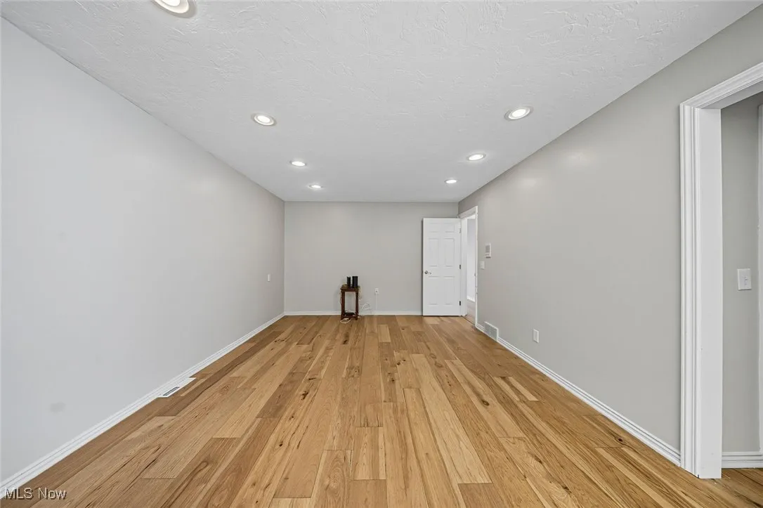 Spare room featuring light wood-style floors, recessed lighting, and a textured ceiling