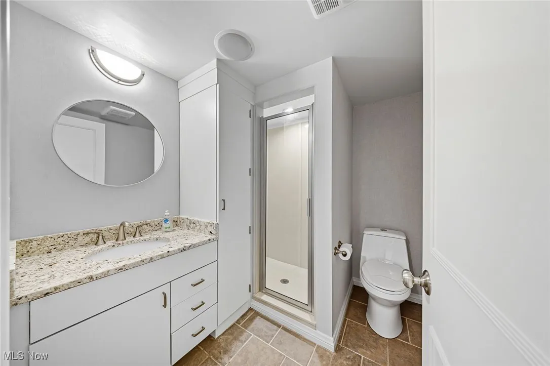 Full bathroom with vanity, a stall shower, and light tile patterned floors