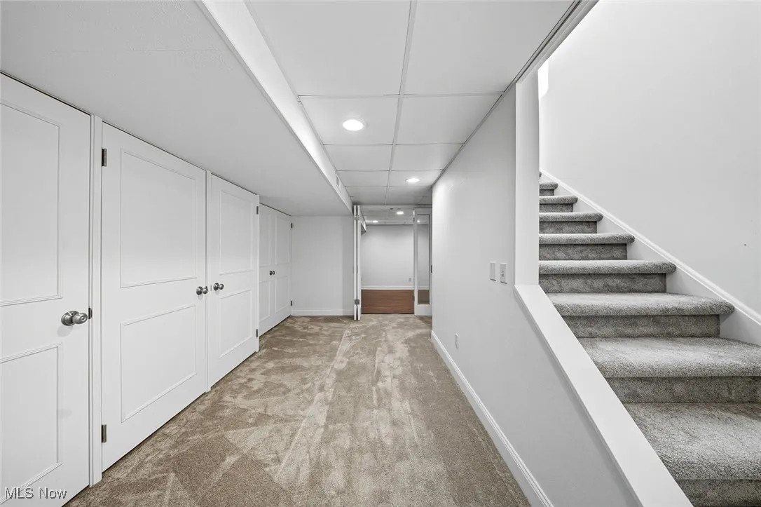 Corridor with light colored carpet, recessed lighting, stairs, and a paneled ceiling