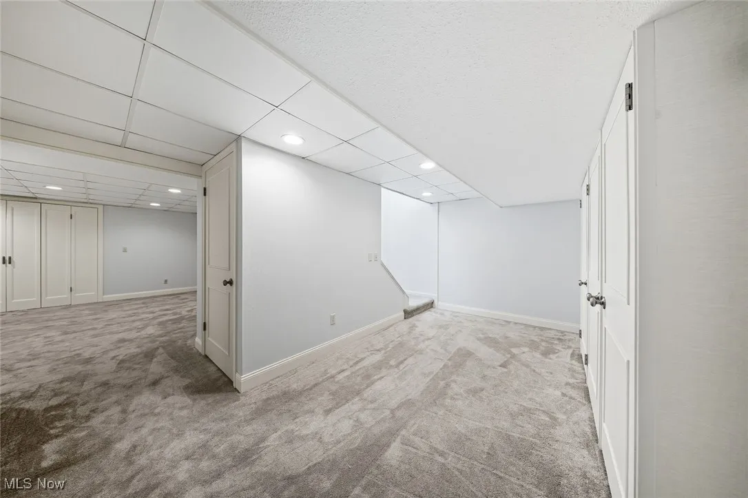 Finished below grade area featuring light carpet, a drop ceiling, and recessed lighting