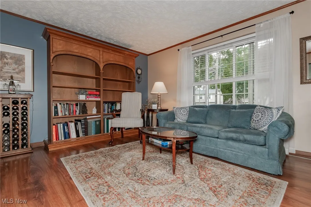 Sitting room with ornamental molding, a textured ceiling, and dark wood-type flooring