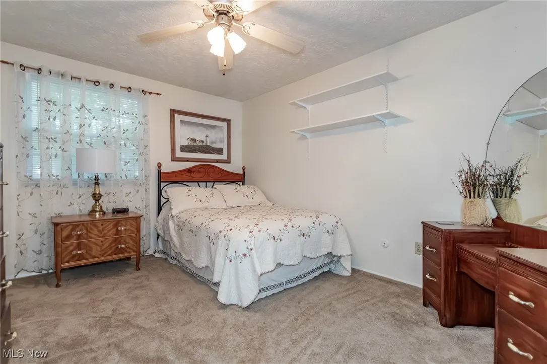 Bedroom featuring a textured ceiling, light carpet, and a ceiling fan