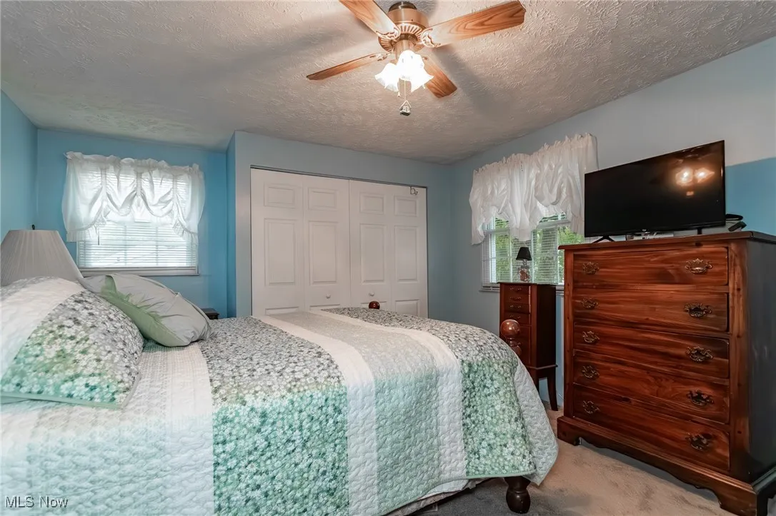 Bedroom with carpet flooring, a textured ceiling, ceiling fan, and a closet