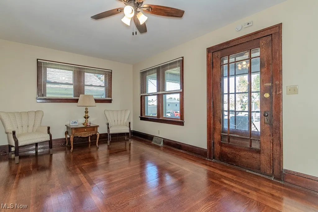 Sitting room featuring healthy amount of natural light, dark wood-type flooring, and ceiling fan