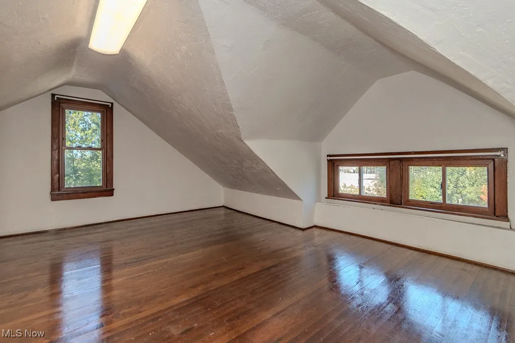 Additional living space featuring dark wood-style flooring, lofted ceiling, and a textured ceiling