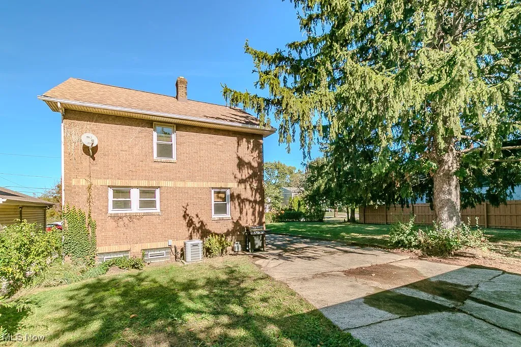 Back of property with a chimney, brick siding, and a patio
