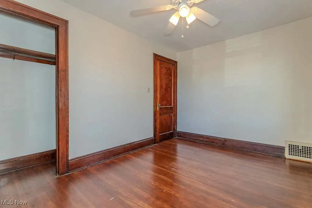 Unfurnished bedroom featuring dark wood finished floors, a ceiling fan, and a closet