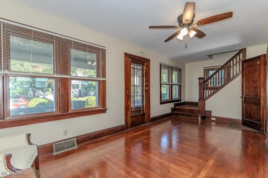 Unfurnished living room with dark wood-type flooring, a ceiling fan, and stairs