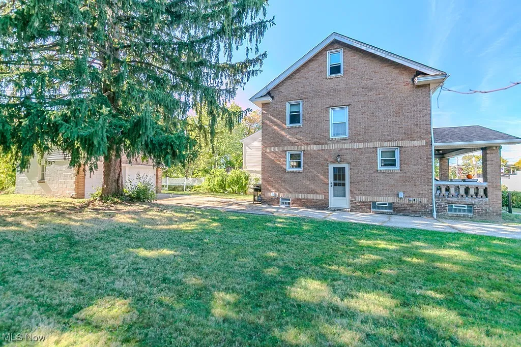 Back of property featuring brick siding, a yard, and a patio area
