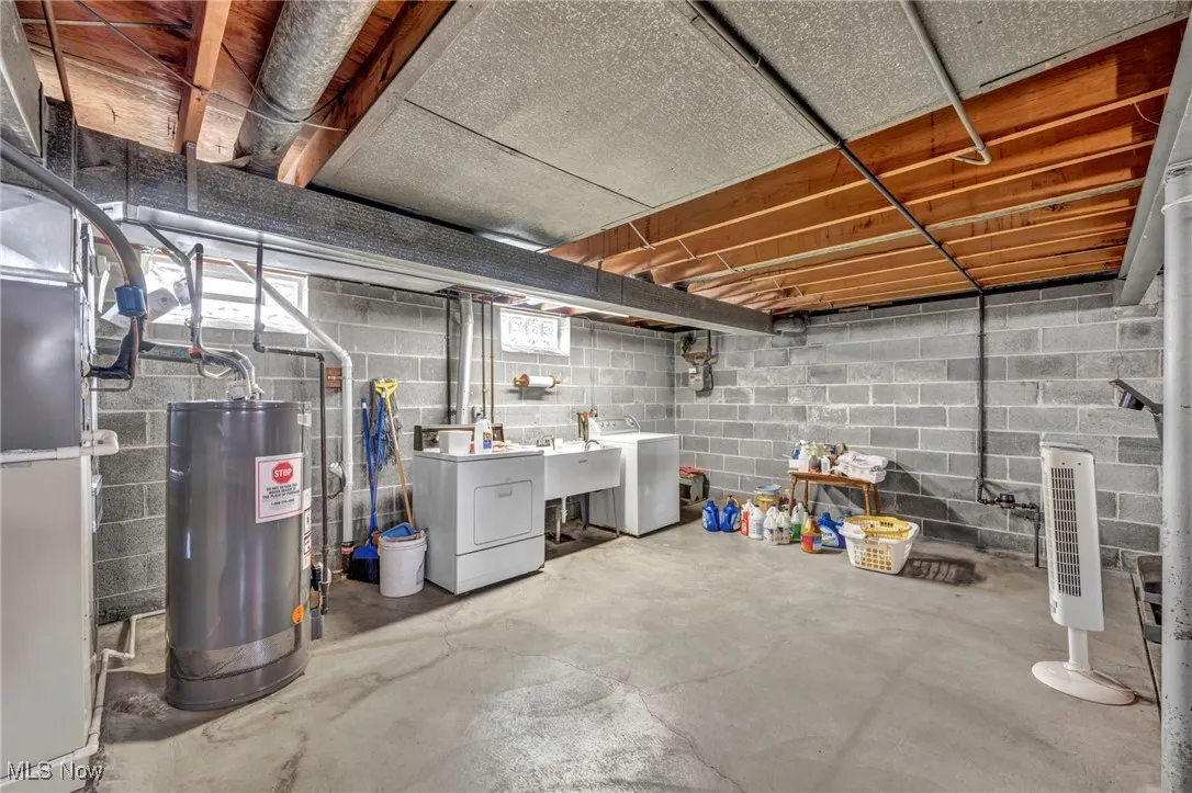 Unfinished below grade area with gas water heater, heating unit, and washing machine and dryer
